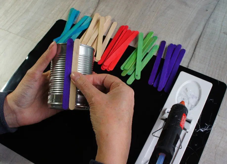 adding popsicle sticks to tin can