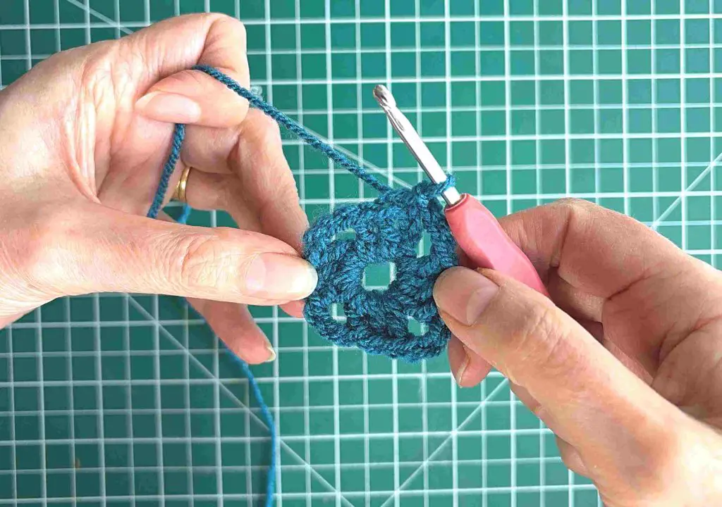 slip stitch finishing first round of granny square in blue
